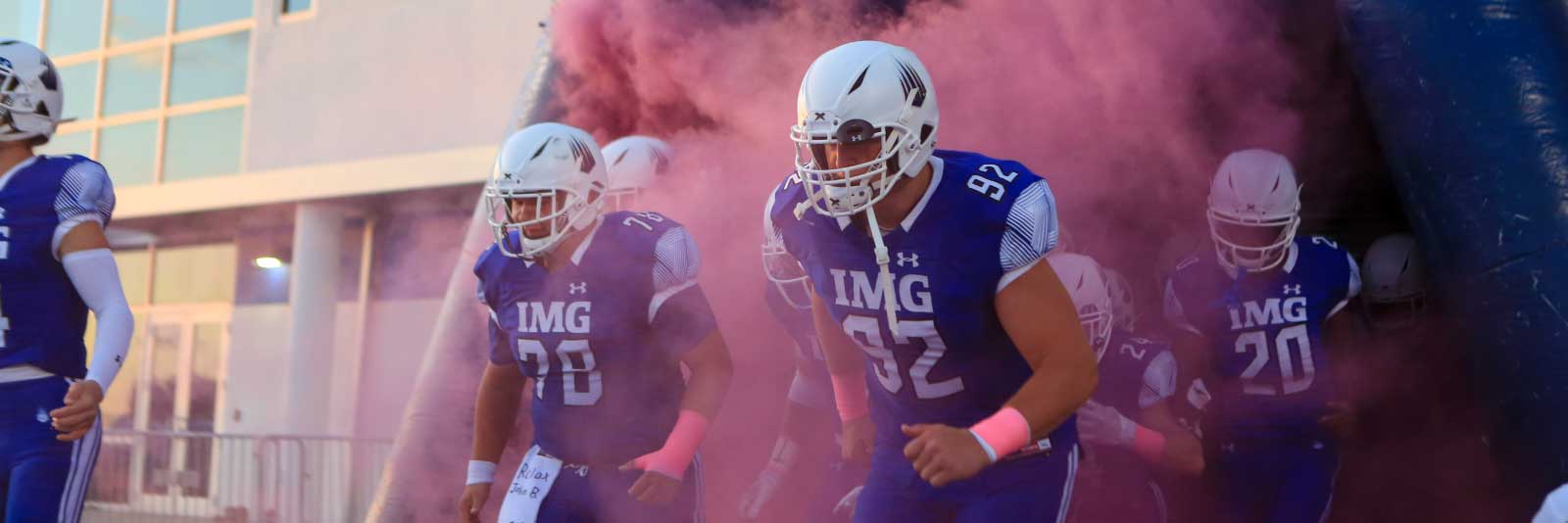 Football players running into football stadium